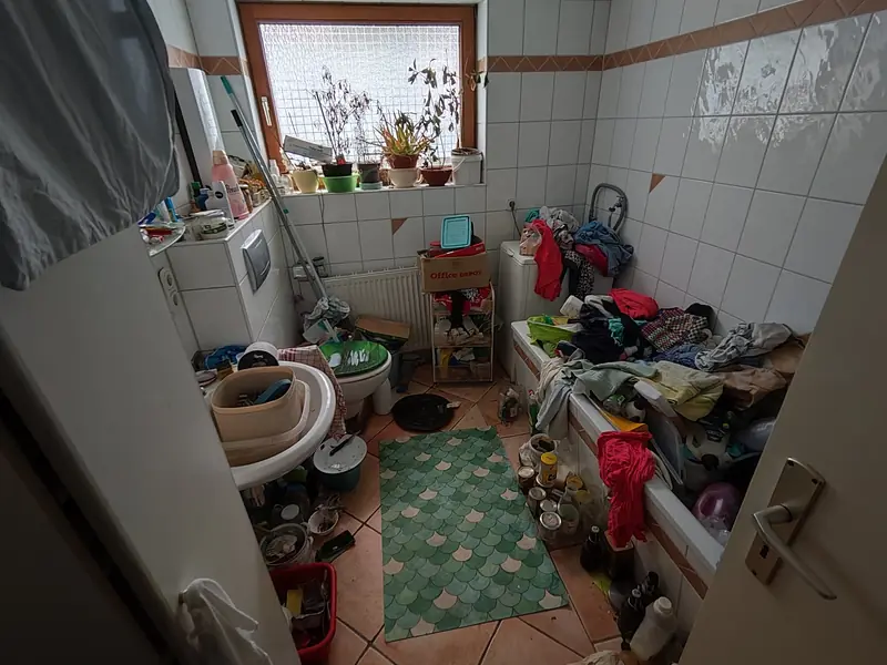 Bad vor der Räumung: Wanne und Boden voller Wäsche und Flaschen